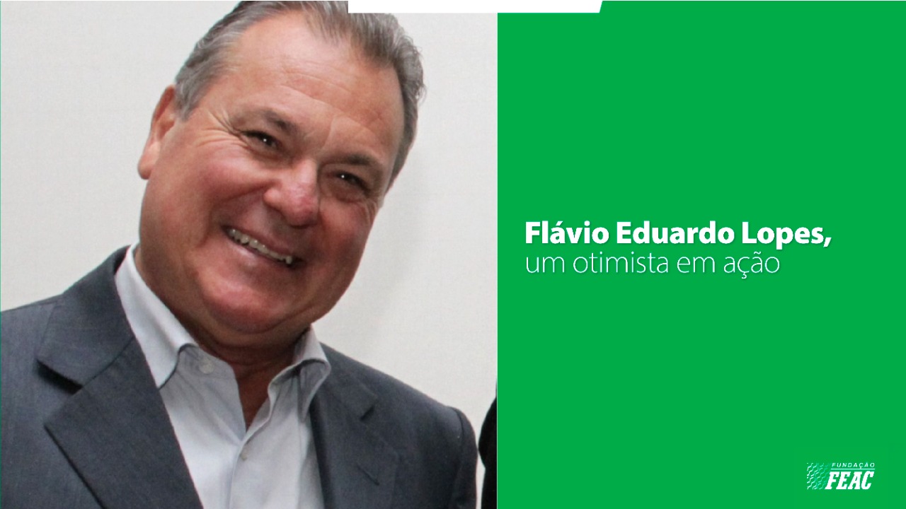 Foto de Flávio Eduardo Lopes, um homem branco de cabelos grisalhos, usando um terno cinza e uma camisa branca, sorrindo.