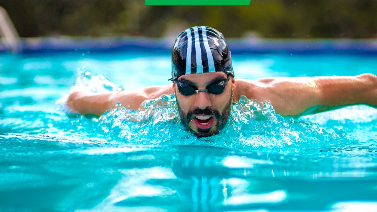 Foto de Daniel Dias nadando em uma piscina. Ele usa touca e óculos de natação.